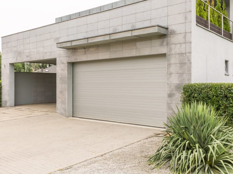 Big grey house with a drive way and a parking garage