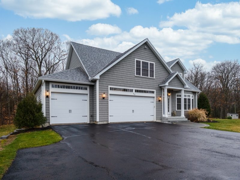 A gray-walled suburban house with white asphalt driveway